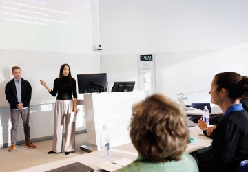 Students in front of a presentation in a classroom, addressing the shark tank judges in the Legal Financial Arbitrage class