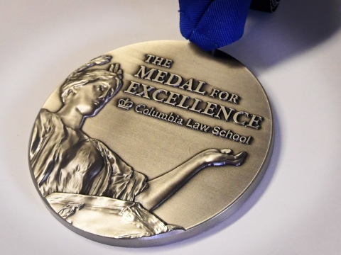 The Law School's Medal for Excellence on a blue ribbon, featuring a relief of Alma Mater.